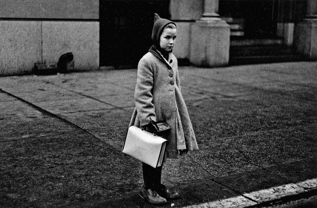 "Girl With A Pointy Hood And White Schoolbag At The Curb, N.Y.C." by Diane Arbus.